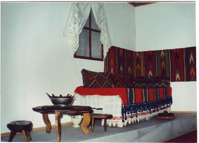 Interior etnografic cu textile, masă joasă și obiecte gospodărești, imagine de arhivă